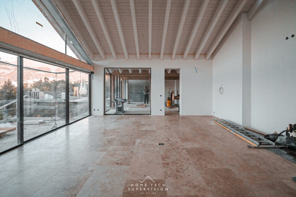 Séjour du chalet sous charpente blanche, sol en pierre – Crans-Montana