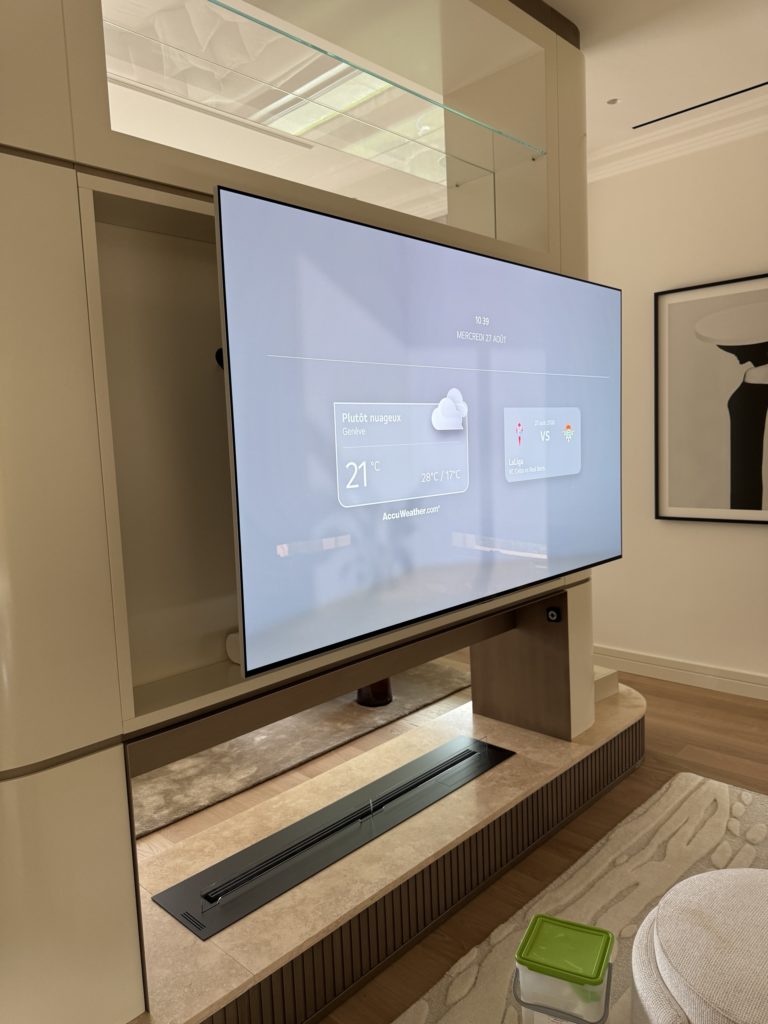 Écran sur bras motorisé orienté vers le canapé, cloison laquée de la TV room