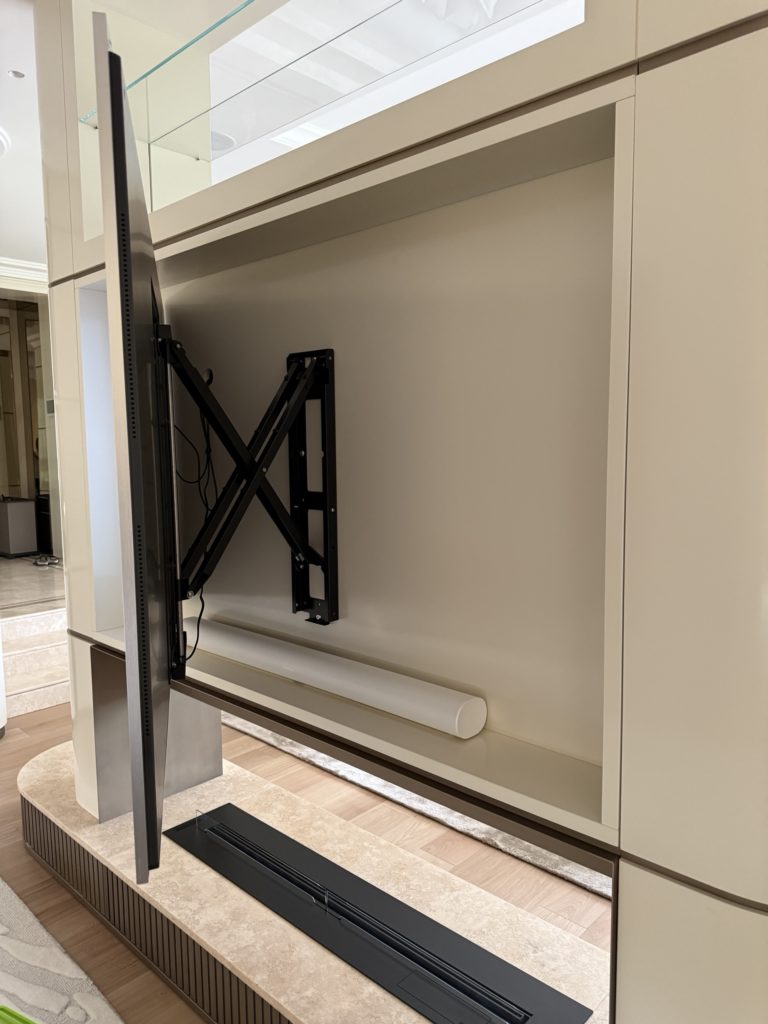 Bras motorisé articulé derrière l’écran, niche laquée et barre de son Sonos Arc