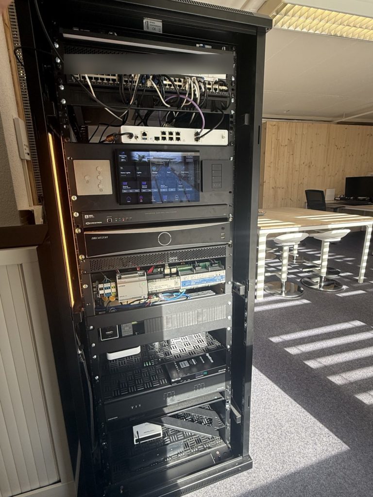 Baie technique préparée à l'atelier : réseau, processeur Crestron, vidéosurveillance et modules Lutron