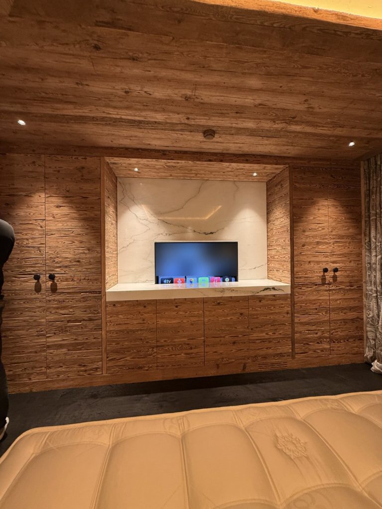Téléviseur sur lift sortant d'un meuble en marbre dans une chambre