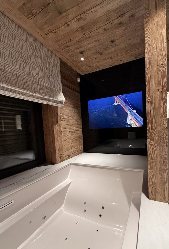 Écran intégré face à la baignoire dans une salle de bains en vieux bois