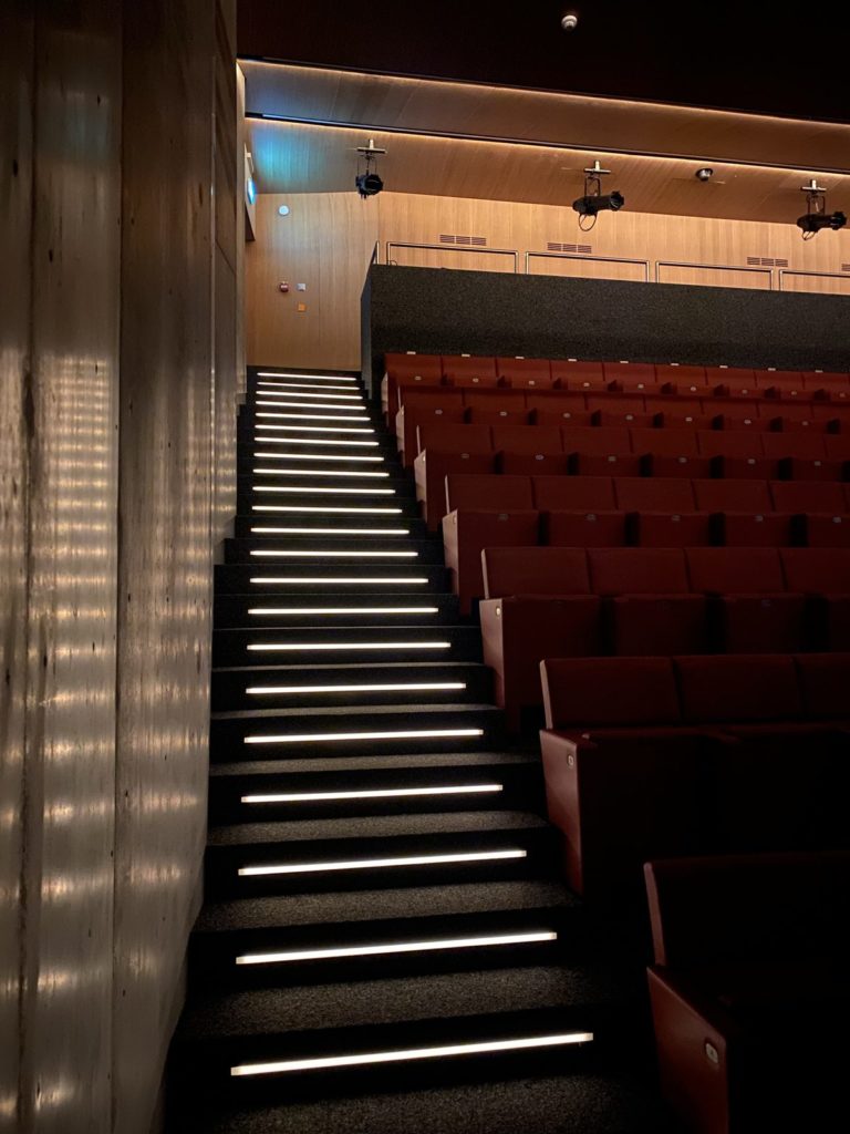 Escalier de l’auditorium avec nez de marches lumineux et fauteuils rouges