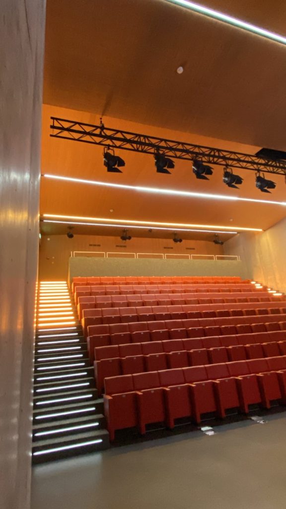Vue de l’auditorium depuis la scène, gradins, marches lumineuses et éclairage de plafond