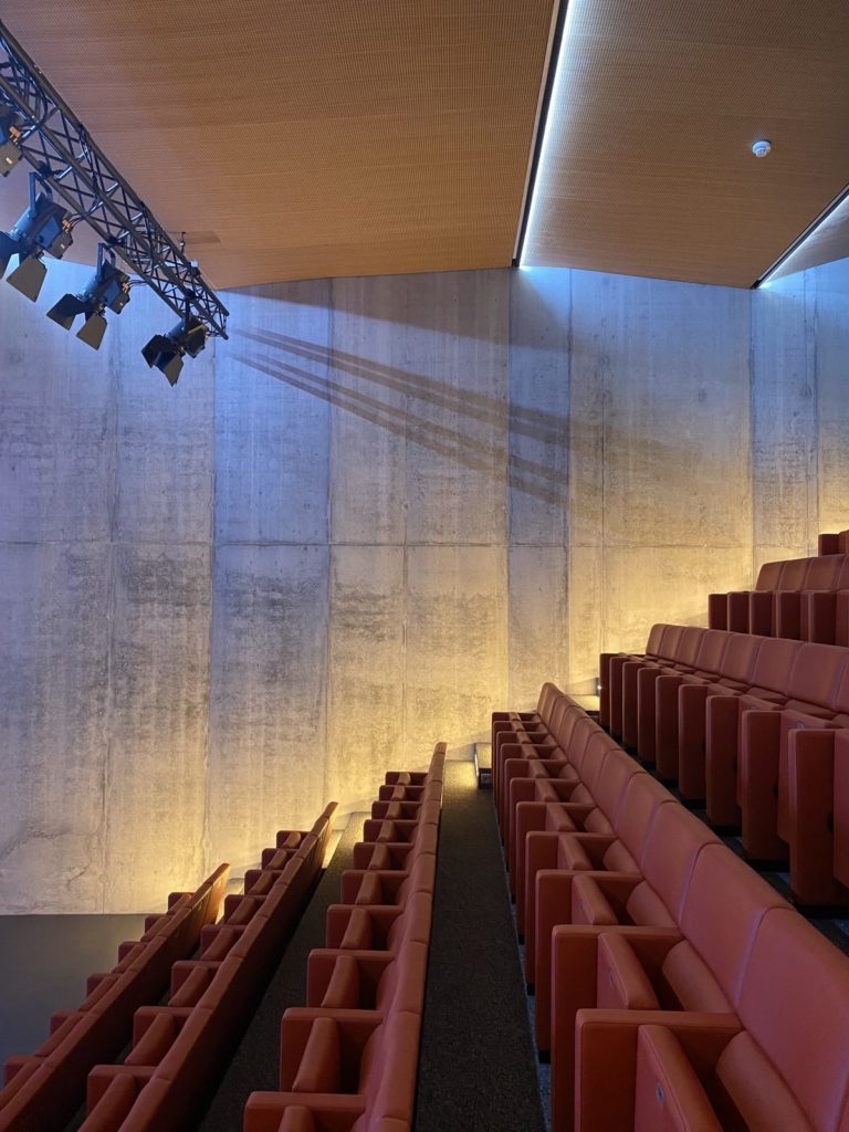 Gradins de l’auditorium, mur en béton éclairé et pont de projecteurs