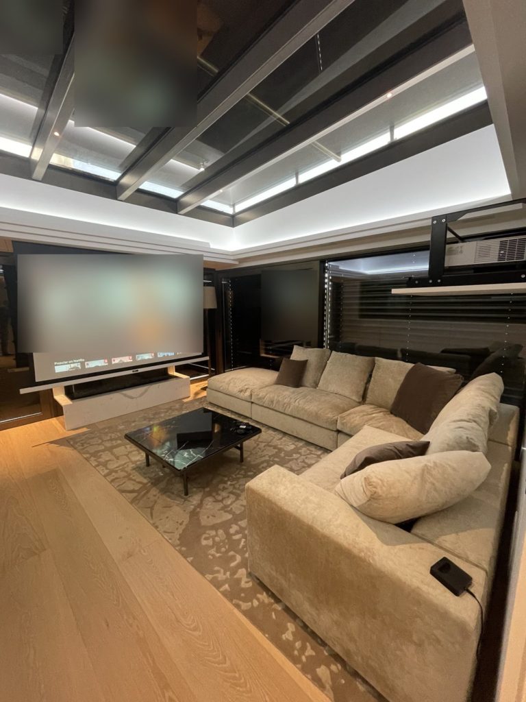 Vue d'ensemble d'une playroom avec écran de projection, canapé d'angle et verrière
