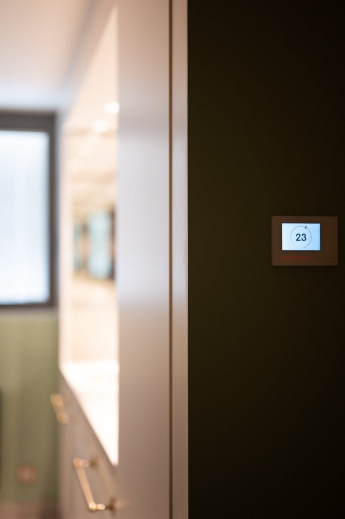 Thermostat Crestron sur mur sombre à l'entrée d'une salle de bains