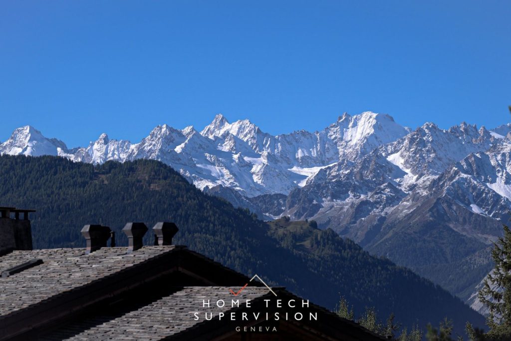 Toit de chalet en lauzes face aux Alpes valaisannes enneigées