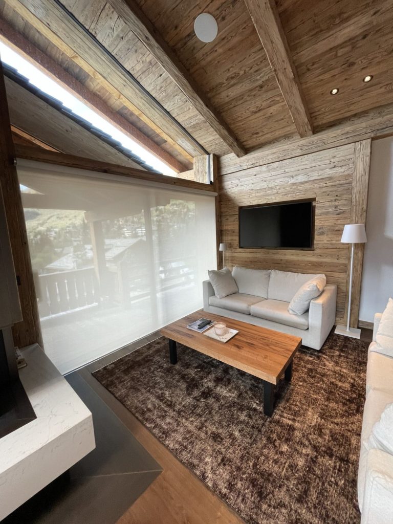 Coin TV du chalet avec store toile Lutron baissé devant la baie vitrée