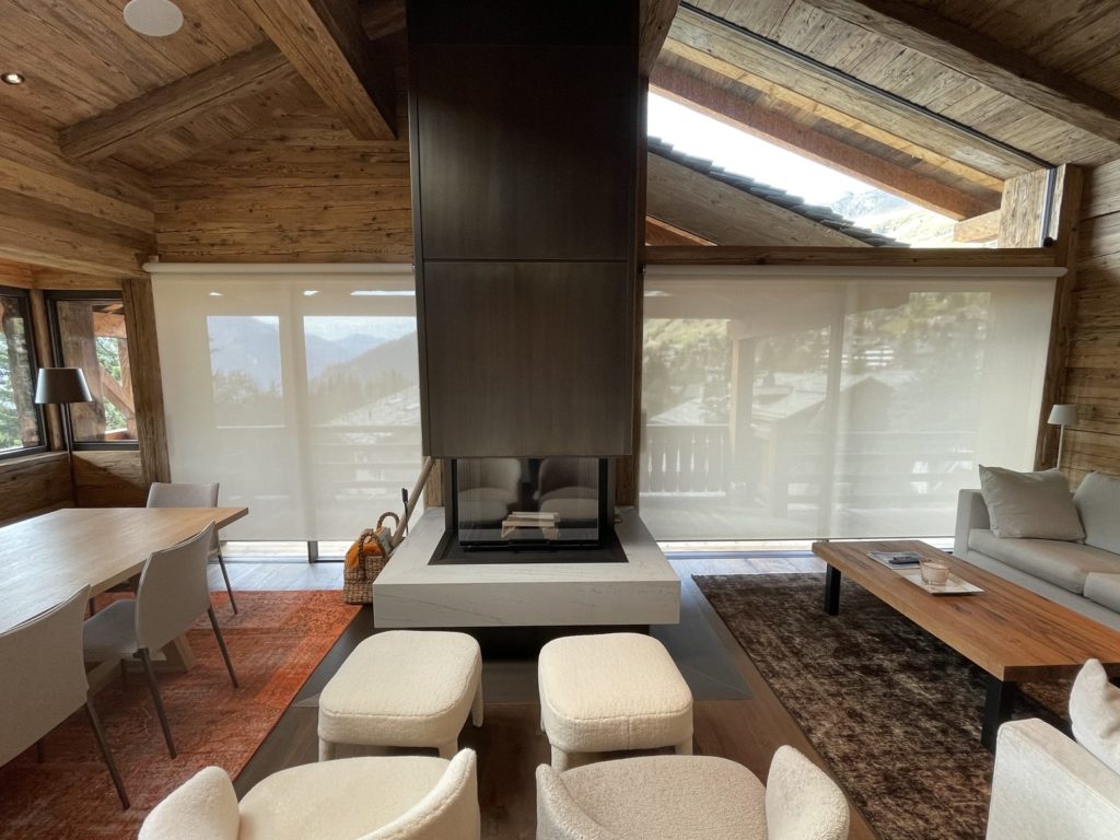 Salon de chalet avec stores toile Lutron entièrement baissés de part et d’autre de la cheminée